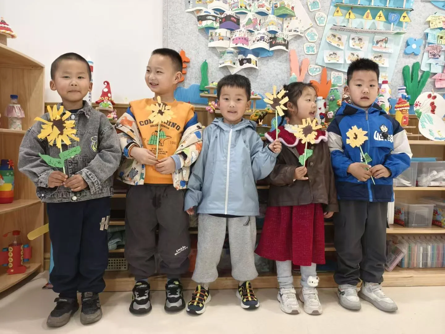 五位小朋友手持向日葵手工作品在教室合影